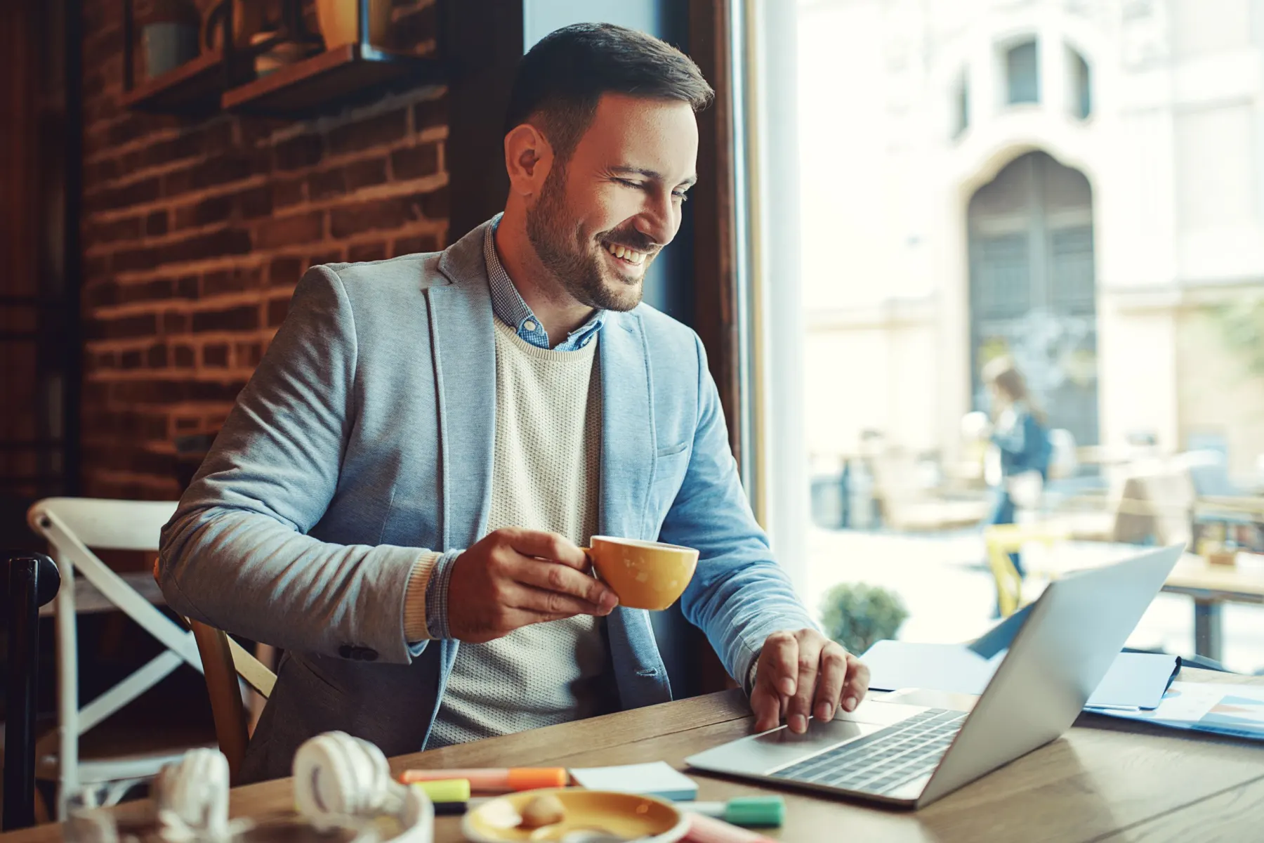 Lächelnder Mann mit Kaffeetasse am Laptop